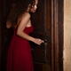 Woman in red dress cautiously listening to the door while opening the... (thumbnail)