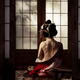 Beautiful geisha sitting in undone red kimono revealing her bare back... (thumbnail)