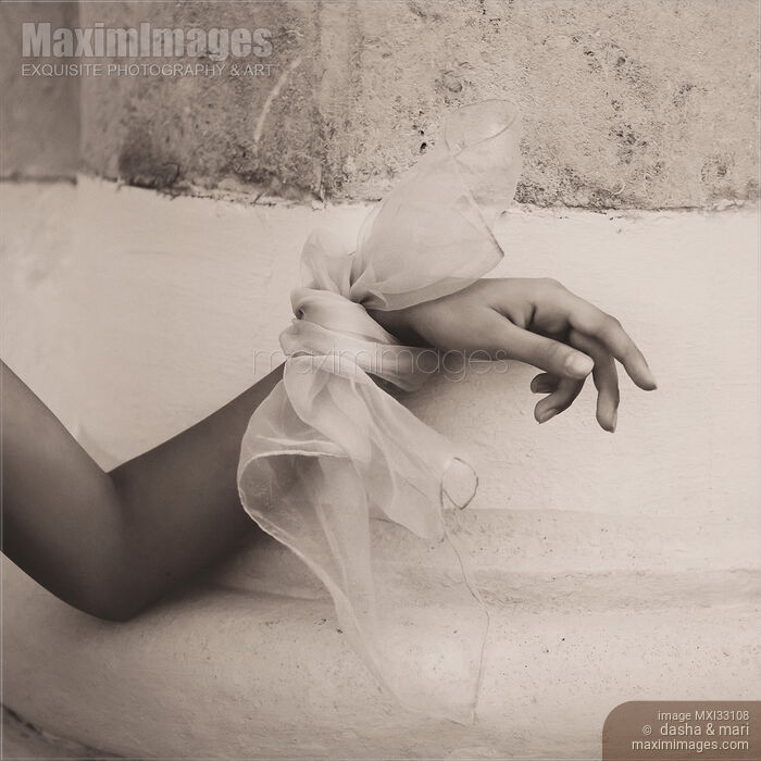 Stock photo of Abstract gentle female hand with a silk bow leaning against rustic old wall Buy commercial use license at MaximImages