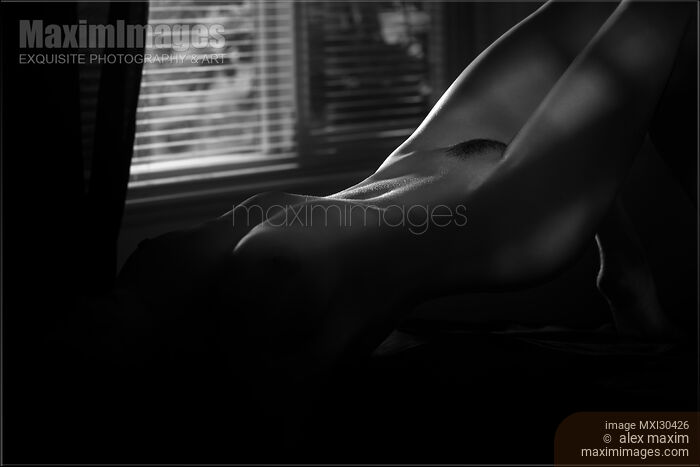 Art nude black and white photo of a sexy beautiful woman body in a dark room lit by a dim light Stock photo of Art nude black and white photo of a sexy beautiful woman body in a dark room lit by a dim light Buy commercial use license at MaximImages