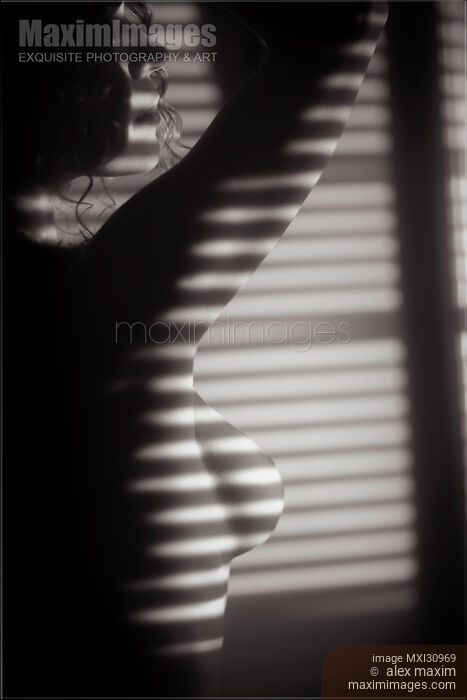 Art nude black and white portrait of a woman standing in light coming through window blinds Stock photo of Art nude black and white portrait of a woman standing in light coming through window blinds Buy commercial use license at MaximImages