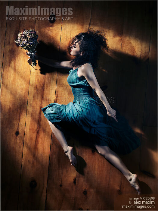 Artistic portrait of woman in blue dress with flower in dynamic leap Stock photo of Artistic portrait of woman in blue dress with flower in dynamic leap Buy commercial use license at MaximImages