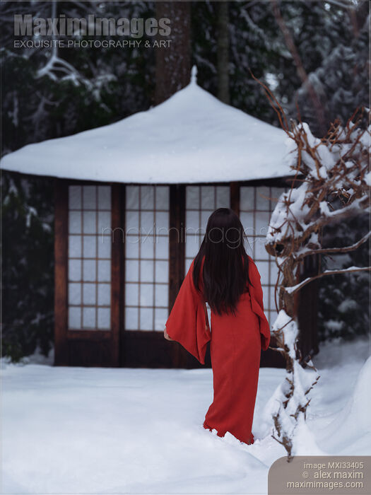 Stock photo of Asian woman in red kimono walking in snow towards little traditional Japanese house or gazebo Buy commercial use license at MaximImages