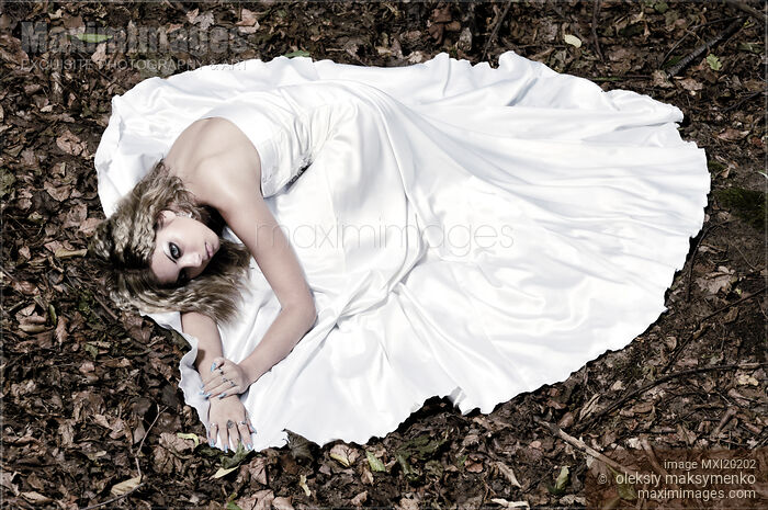 Stock photo of Beautiful Bride in Wedding Gown Lying on Fallen Autumn Leaves Buy commercial use license at MaximImages