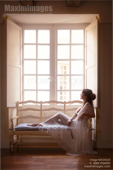 Beautiful lady in sheer white lace nightgown sitting on vintage sofa by a large French window Stock photo of Beautiful lady in sheer white lace nightgown sitting on vintage sofa by a large French window Buy commercial use license at MaximImages