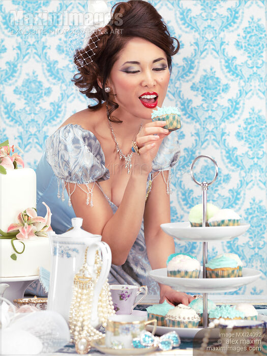 Stock photo of Beautiful lady is about to eat a cupcake at a tea party Buy commercial use license at MaximImages