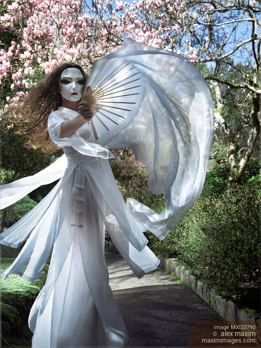 Beautiful mysterious asian woman in face mask and white gown dancing gracefully with silk fans in garden Stock photo of Beautiful mysterious asian woman in face mask and white gown dancing gracefully with silk fans in garden Buy commercial use license at MaximImages
