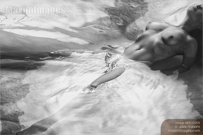 Beautiful nude woman lying in shiny water with her chest arched up and her legs apart Black and white Stock photo of Beautiful nude woman lying in shiny water with her chest arched up and her legs apart Black and white Buy commercial use license at MaximImages