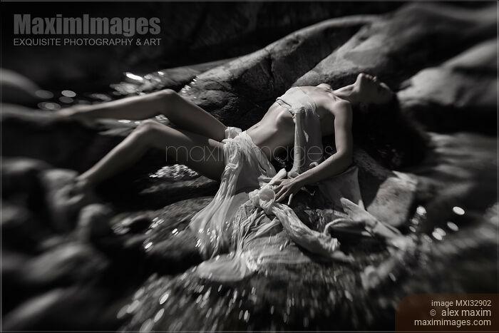 Beautiful nude woman lying on river rocks her naked barely covered body blending with rocky landscape Black and white Stock photo of Beautiful nude woman lying on river rocks her naked barely covered body blending with rocky landscape Black and white Buy commercial use license at MaximImages