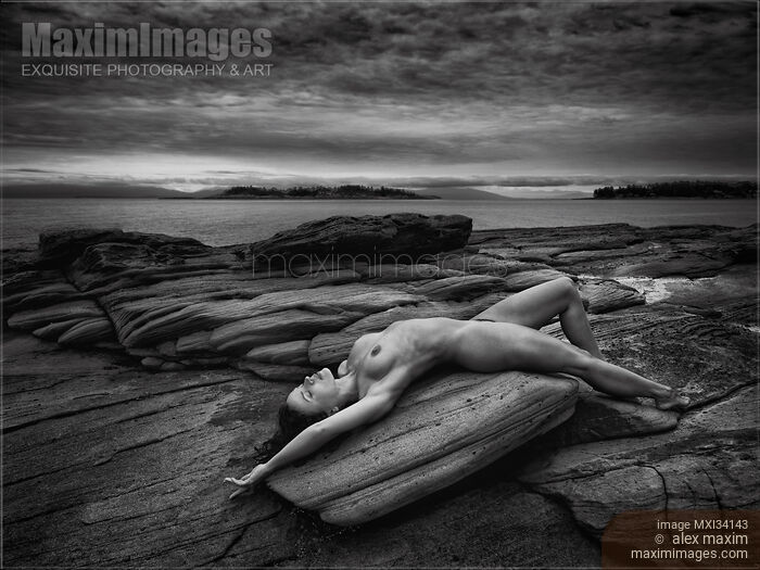 Beautiful nude young woman lying naked stretched on ocean shore rock in graceful relaxed pose Black and white Stock photo of Beautiful nude young woman lying naked stretched on ocean shore rock in graceful relaxed pose Black and white Buy commercial use license at MaximImages