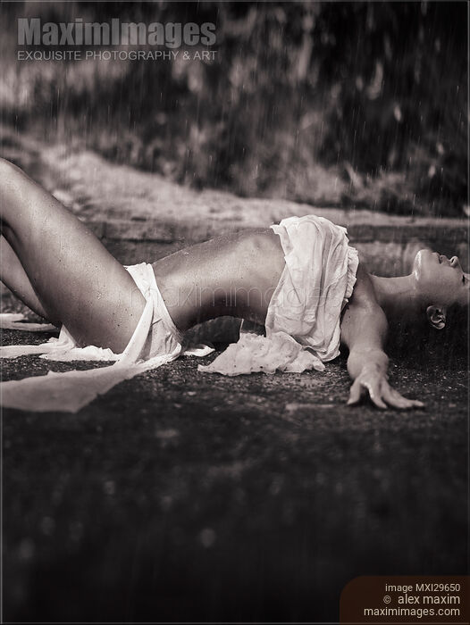 Beautiful sexy young woman in beach wear lying on the ground under pouring rain Stock photo of Beautiful sexy young woman in beach wear lying on the ground under pouring rain Buy commercial use license at MaximImages
