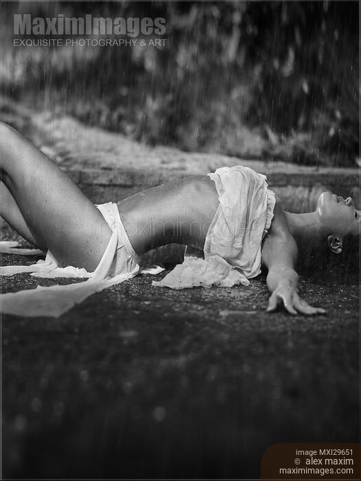 Stock photo of Beautiful sexy young woman in beach wear lying under pouring rain Black and white Buy commercial use license at MaximImages