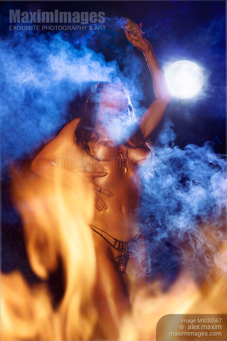 Stock photo of Beautiful tribal aboriginal woman dancing naked at night in full moon surrounded by smoke and fire flames Buy commercial use license at MaximImages