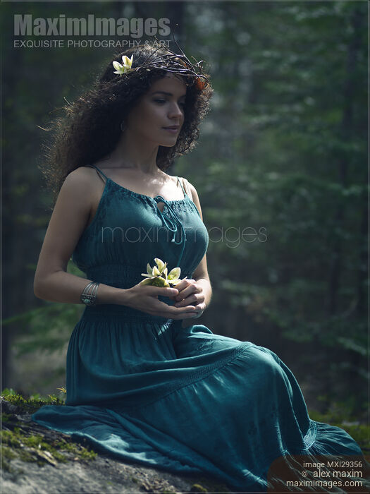 Beautiful woman in green dress sitting in the nature with a flower in her hands Stock photo of Beautiful woman in green dress sitting in the nature with a flower in her hands Buy commercial use license at MaximImages