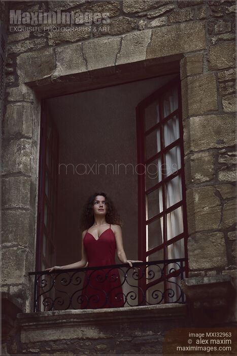 Beautiful woman in red dress standing in open window of medieval French house looking outside Stock photo of Beautiful woman in red dress standing in open window of medieval French house looking outside Buy commercial use license at MaximImages