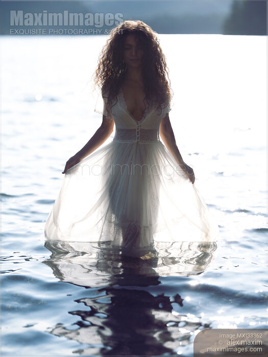 Beautiful woman in sheer white lace dress walking out of water like a Greek Goddess Stock photo of Beautiful woman in sheer white lace dress walking out of water like a Greek Goddess Buy commercial use license at MaximImages