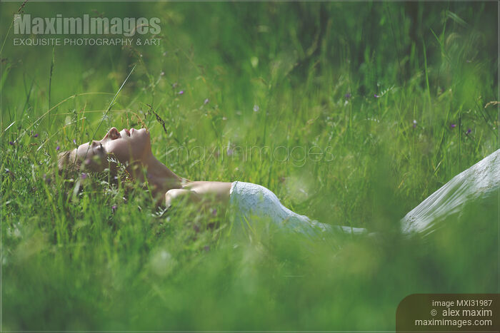 Beautiful woman lying in green grass with her eyes closed facing the sunlight in summertime nature scenery Stock photo of Beautiful woman lying in green grass with her eyes closed facing the sunlight in summertime nature scenery Buy commercial use license at MaximImages