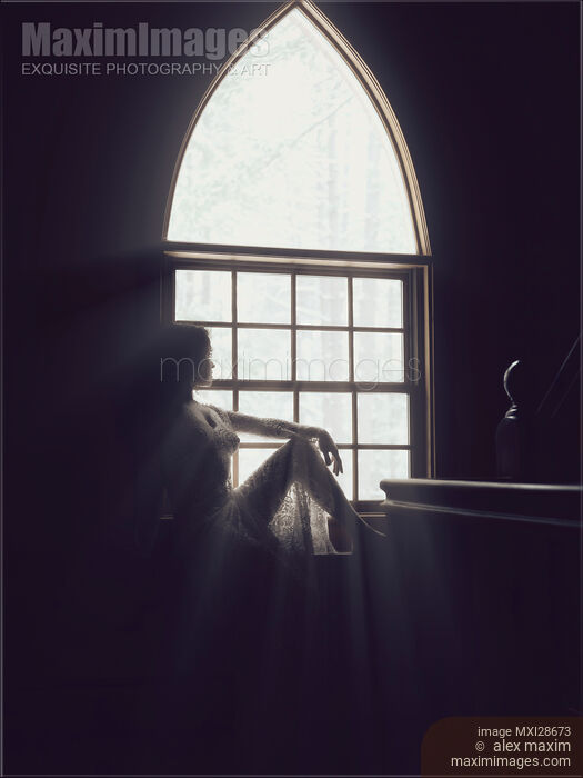 Beautiful woman sitting on a window sill in bright sunlight Stock photo of Beautiful woman sitting on a window sill in bright sunlight Buy commercial use license at MaximImages