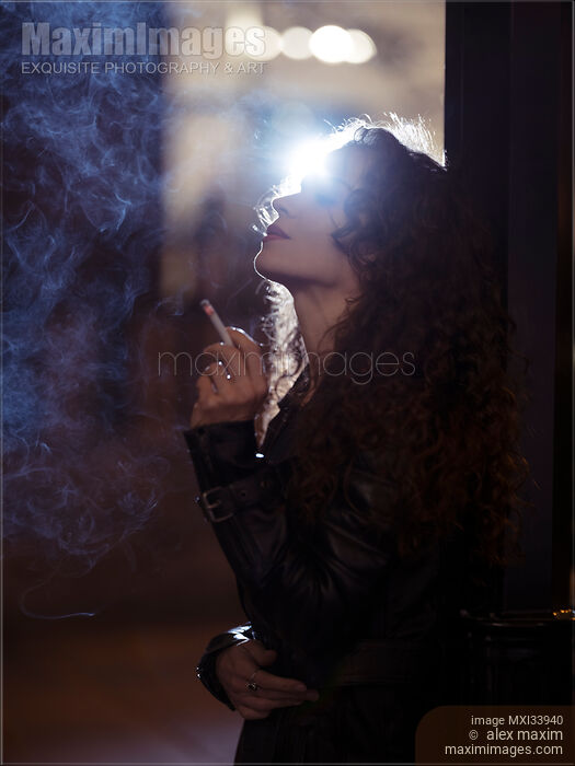 Beautiful woman smoking a cigarette standing on a night city street Stock photo of Beautiful woman smoking a cigarette standing on a night city street Buy commercial use license at MaximImages
