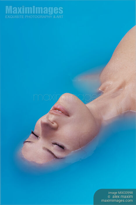 Beautiful young woman face lying half submerged in turquoise blue water abstract beauty portrait Stock photo of Beautiful young woman face lying half submerged in turquoise blue water abstract beauty portrait Buy commercial use license at MaximImages