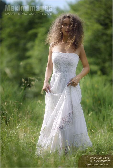 Beautiful young woman in white summer dress walking through a field of green grass in sunny nature scenery Stock photo of Beautiful young woman in white summer dress walking through a field of green grass in sunny nature scenery Buy commercial use license at MaximImages