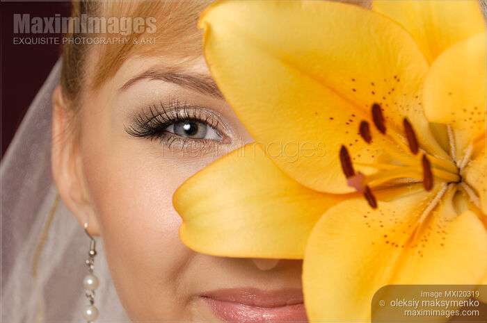 Stock photo of Beautiful Young Woman with Yellow Lily Closeup of Eyes Buy commercial use license at MaximImages