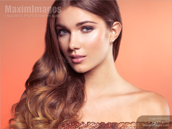 Stock photo of Beauty face portrait of a young woman with natural look on long wavy silky brown hair Buy commercial use license at MaximImages