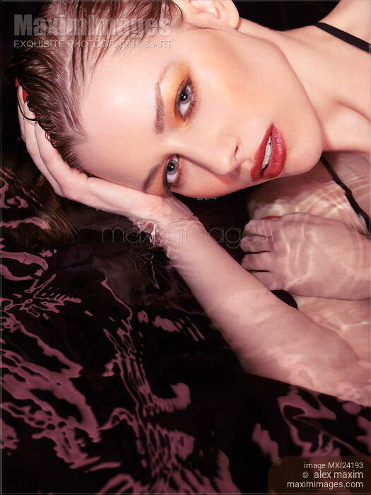 Beauty portrait of a woman wearing makeup and red lipstick lying in water Stock photo of Beauty portrait of a woman wearing makeup and red lipstick lying in water Buy commercial use license at MaximImages