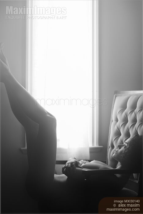 Stock photo of Black and white art nude portrait of beautiful woman lying naked in armchair with her legs raised Buy commercial use license at MaximImages