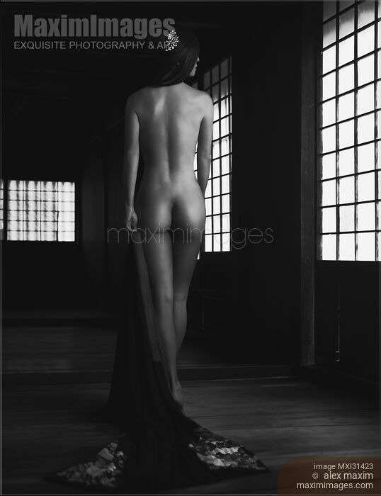Stock photo of Black and white fine art nude Japanese woman undressed in dark house her nude back glowing in soft light of shoji screens Buy commercial use license at MaximImages