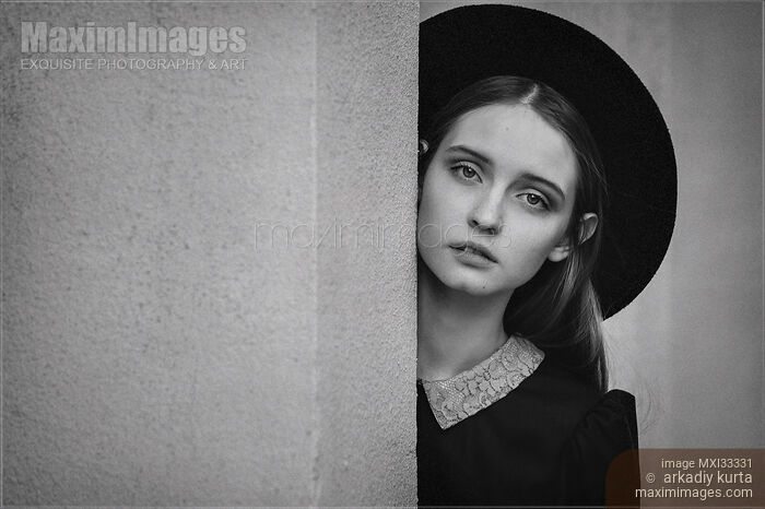 Stock photo of Black and white portrait of a girl with an expressive look on her face wearing a black hat Buy commercial use license at MaximImages