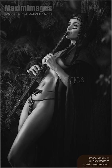 Stock photo of Black and white sensual portrait of a sexy Native American tribal woman playing bamboo flute in the nature Buy commercial use license at MaximImages