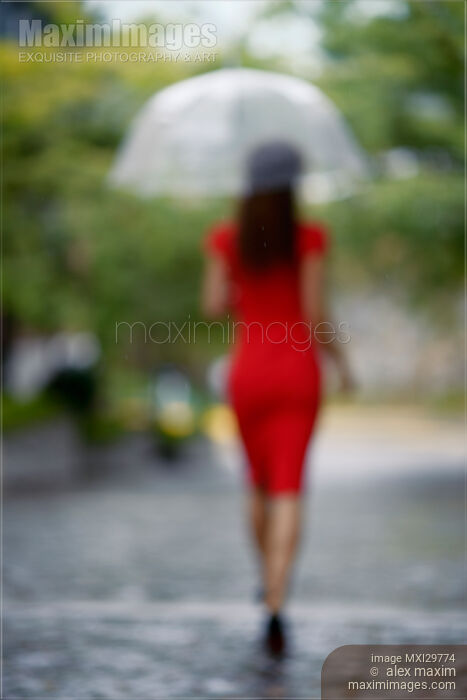 Blurred back of woman in red dress with umbrella walking away in the rain Stock photo of Blurred back of woman in red dress with umbrella walking away in the rain Buy commercial use license at MaximImages