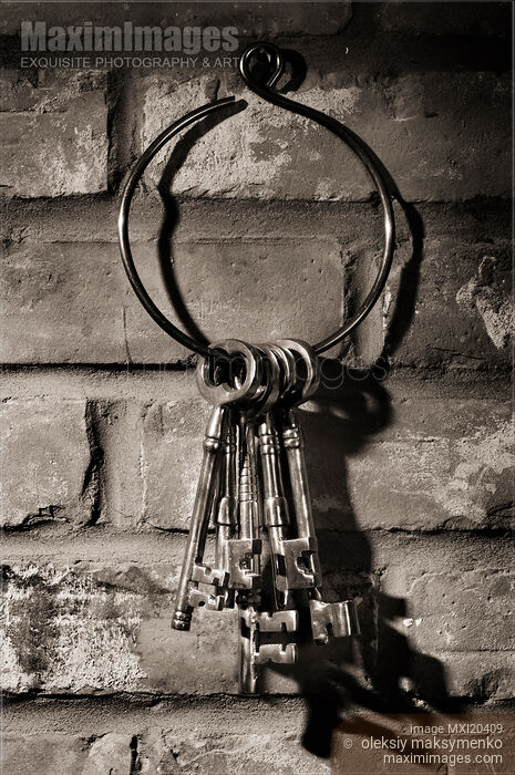 Photo of Bunch of antique keys hanging on brick wall black and white