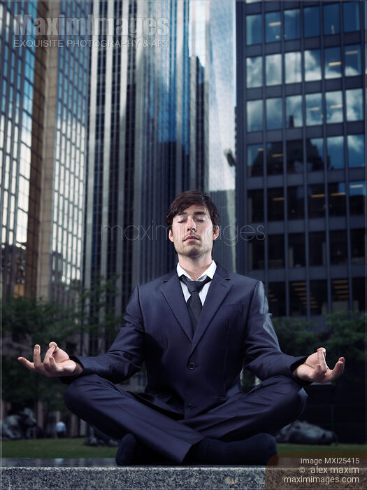 Stock photo of Businessman meditating with office buildings behind him Buy commercial use license at MaximImages