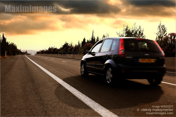 Stock photo of Car driving by highway at sunset Buy commercial use license at MaximImages