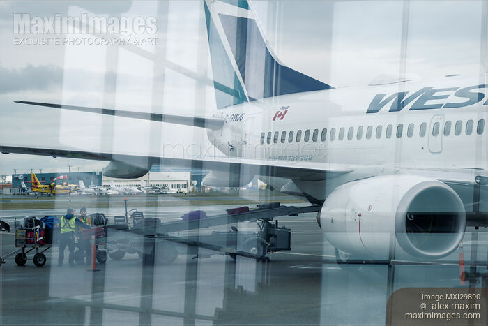 Stock photo of Checked in luggage being loaded on a WestJet airplane at an airport Buy commercial use license at MaximImages