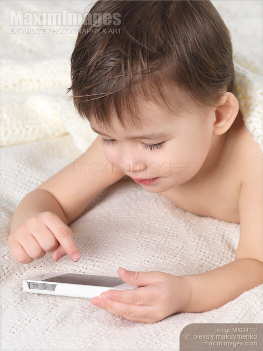 Stock photo of Child with an iPhone in bed Buy commercial use license at MaximImages