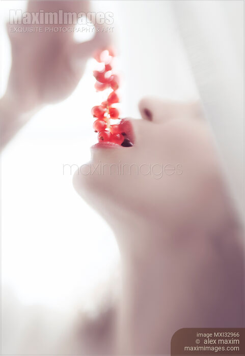 Stock photo of Closeup of a woman taking bright red currants in her sensual mouth with open lips Buy commercial use license at MaximImages