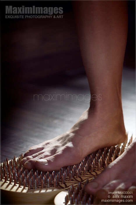 Stock photo of Closeup of a woman with bare feet standing on Sadhu Board Yogic board of nails Buy commercial use license at MaximImages