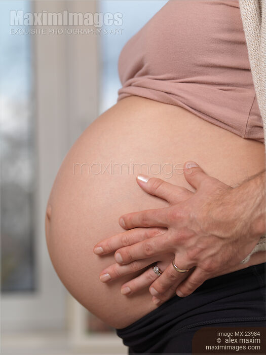 Closeup of man and woman's hands on pregnant belly Stock photo of Closeup of man and woman's hands on pregnant belly Buy commercial use license at MaximImages