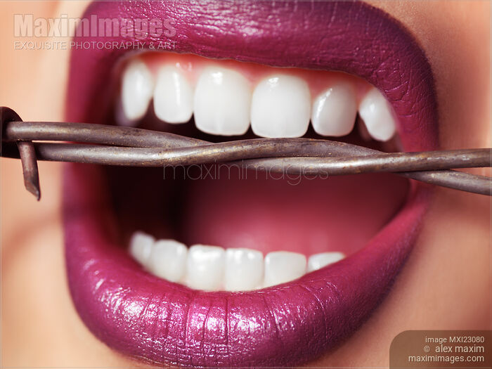 Stock photo of Closeup of Woman's Mouth Biting on Barbed Wire Buy commercial use license at MaximImages