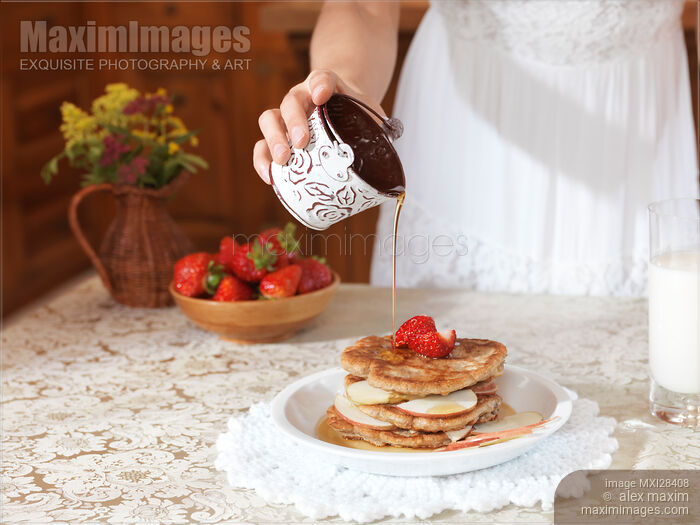 Closeup of young woman pouring maple syrup on pancakes Stock photo of Closeup of young woman pouring maple syrup on pancakes Buy commercial use license at MaximImages