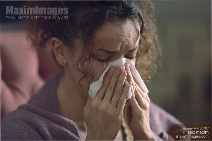 Closeup portrait of woman blowing her runny nose in paper tissue Stock photo of Closeup portrait of woman blowing her runny nose in paper tissue Buy commercial use license at MaximImages