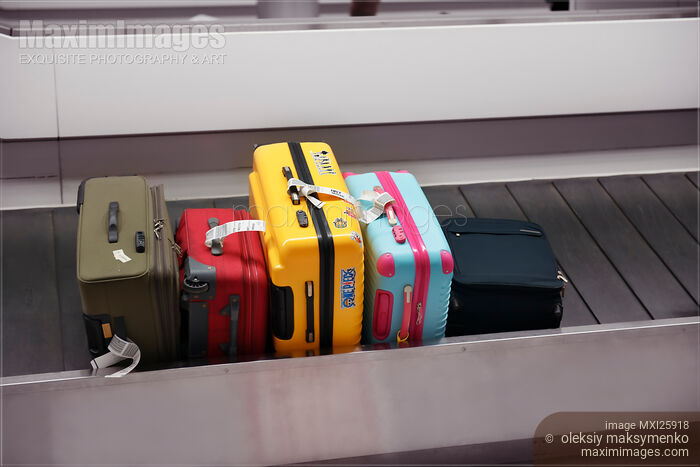 Stock photo of Colorful suitcases on airport baggage claim conveyor Buy commercial use license at MaximImages