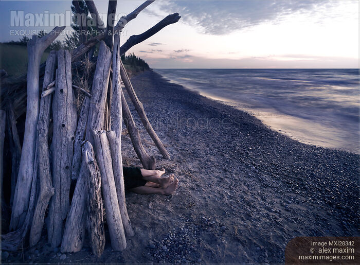 Stock photo of Couple in driftwood shack at the beach Buy commercial use license at MaximImages