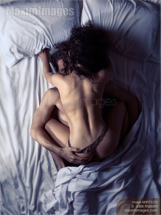 Stock photo of Couple making love in bed in dimly lit bedroom Buy commercial use license at MaximImages