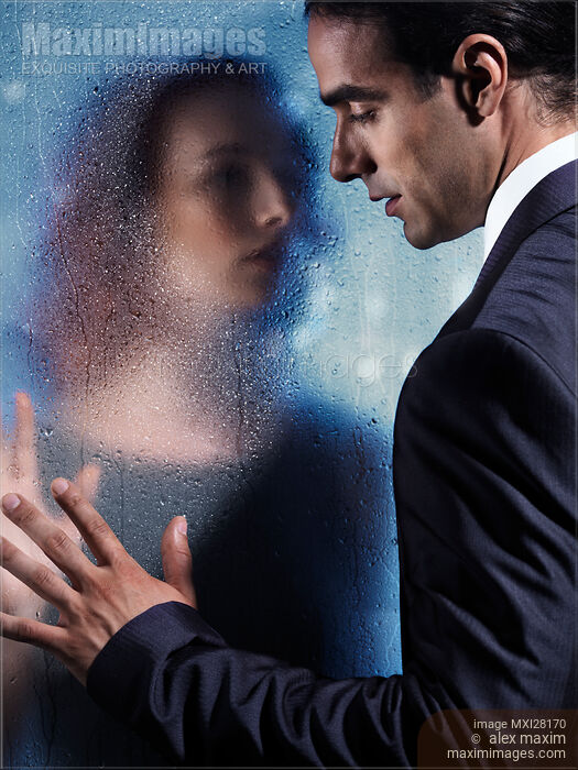 Stock photo of Couple separated by wet glass pane. Relationship drama romantic concept. Buy commercial use license at MaximImages
