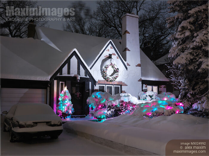 Stock photo of Covered with snow house with Christmas lights Buy commercial use license at MaximImages