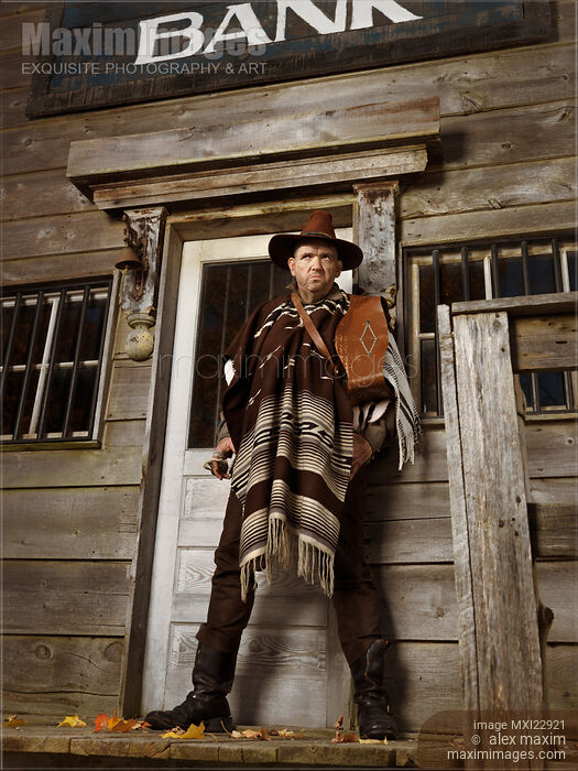 Stock photo of Cowboy Standing Outside of a Bank Building Notorious villain and robber in Wild west style Buy commercial use license at MaximImages